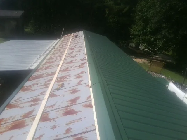 Old rusted panels beside newly installed green metal roofing — Wind Damage Roof Repair by Roofing Brothers in Vilas
