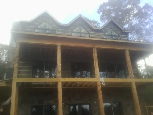 Dormers and porch framing on a large log home under construction — Roof Coating work by our crew in Vilas