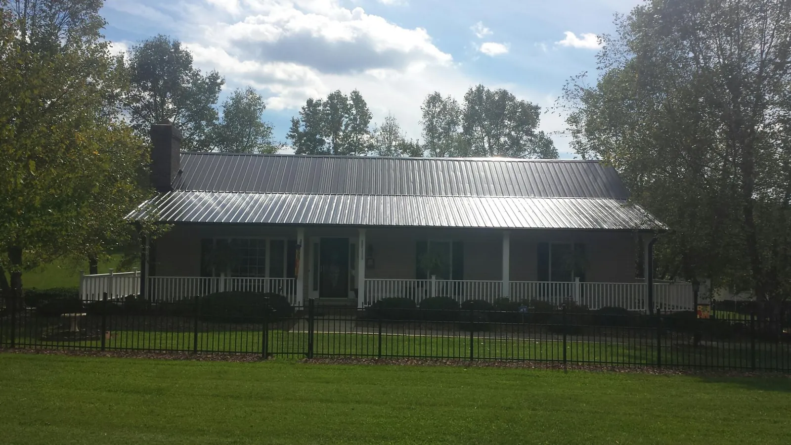 Gray metal roof on a brick ranch with a full width front porch — Gutter Guard Installation work by our crew in Vilas