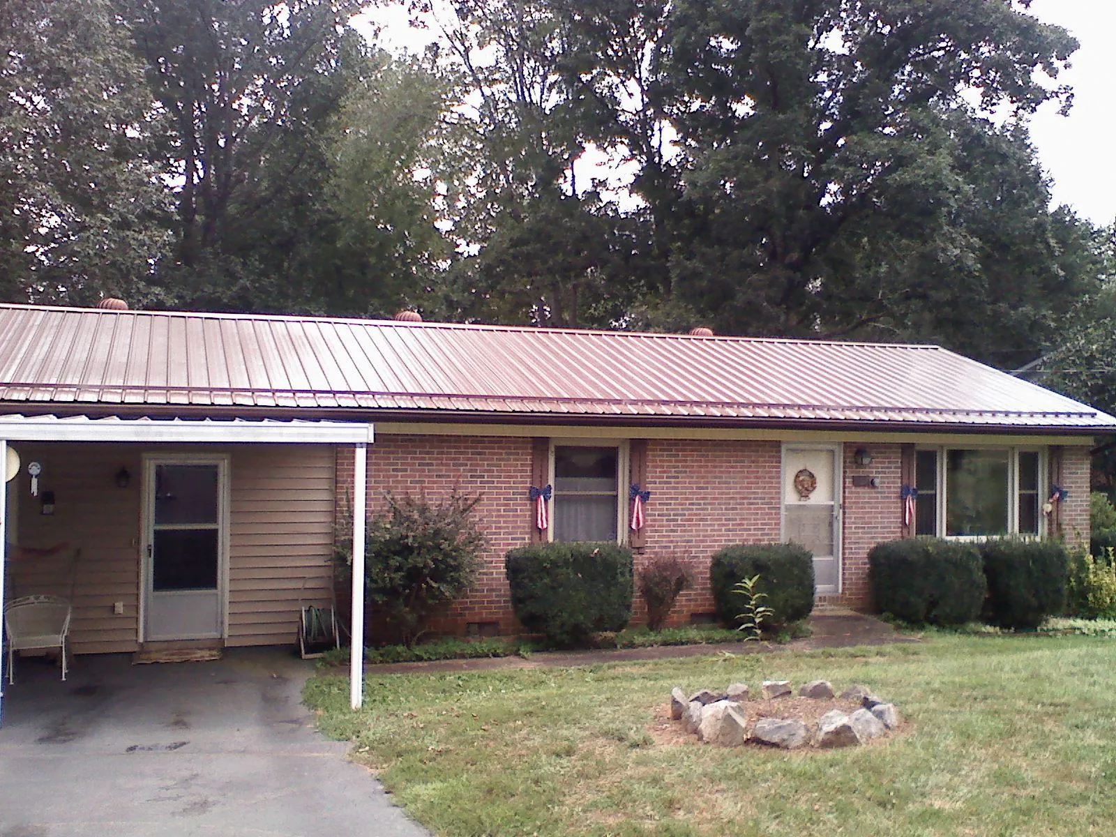 Bronze metal roof and carport on a brick ranch home — Roof Repair work by our crew in Vilas
