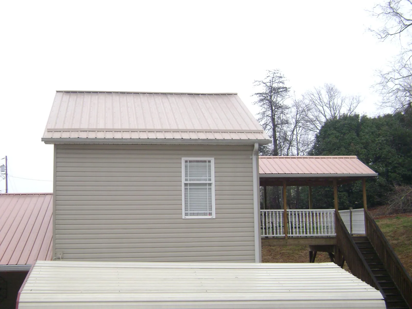 Tan metal roofs on a two story addition and attached porch, from a Roof Replacement job in Vilas